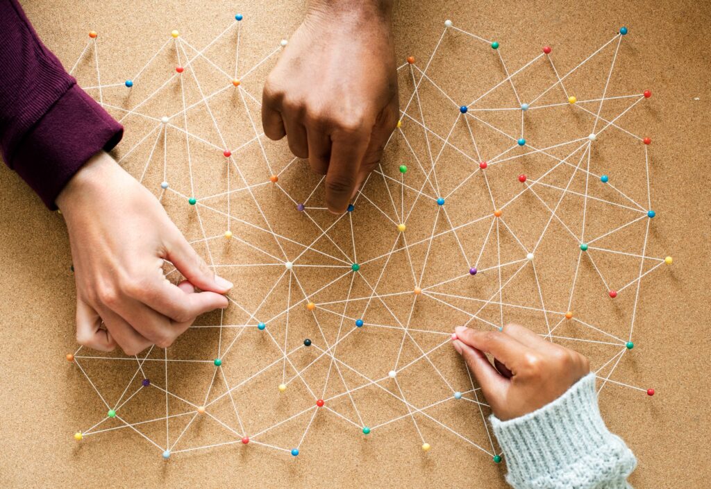 People connecting pins on a cork board with strings